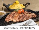 Juicy T-bone steak with grill marks, served with creamy mashed potatoes and a vibrant bowl of chimichurri. Perfect for menus, food blogs, or restaurant ads, showcasing gourmet dining at its finest.