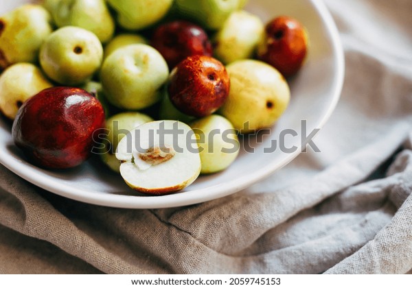 Jujube fruit. top view. Hunnap jujube fruits on a\
white plate on a beige background. close-up. healthy eating\
concept. diabetes fruit.