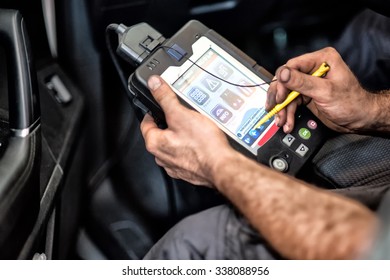 July 02, 2015 - Monza, Lombardy, Italy : Mechanic Using A Car Checker Computer With A Digital Display During Routine Servicing And Maintenance