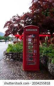  July 16th,2021, Interlaken,Switzerland. View Of A Swisscom Public Phone In Classic UK Style Red Telephone Booth With A Open Book Case Library Captured At The Main Street Of Interlaken ,Switzerland.