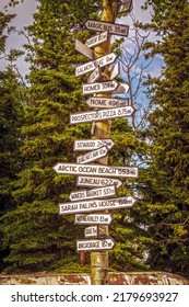 July 2 2022 Denali AK USA Signpost In Healy Alaska With Distances To Magic Bus Nome Seward Sarah Palins House Anchorage And More- Evergreen Trees In Background