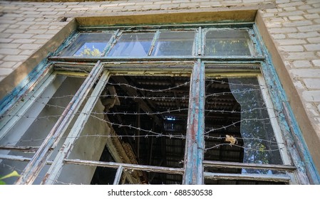 July 2017, Village Dachnoe, Donetsk Region, Ukraine. Destroyed Window At School Canteen Wrapped By Barbed Wire.