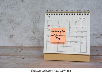 July 2022 calendar on wooden desk with date circle and text on sticky note. The fourth of July, Independence day on 14th July 2022.
