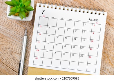 The July 2022 desk calendar with pen on wooden table. - Shutterstock ID 2107809095