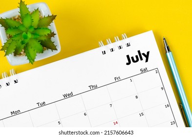 The July 2022 desk calendar and pen with plant pot on yellow background. - Shutterstock ID 2157606643