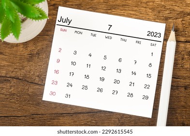 July 2023 Monthly calendar for 2023 year with pen on wooden background.