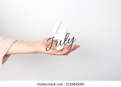 July 4th. Day 4 of month, Calendar date. Calendar Date floating over female hand on grey background. Summer month, day of the year concept