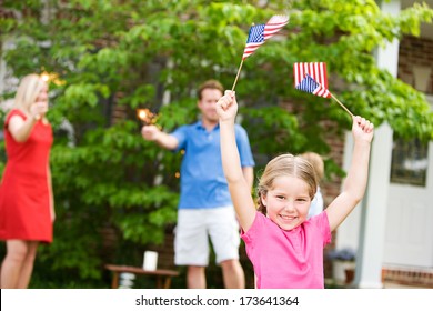 July 4th: Excited Little Girl Holding Flags in the Air - Powered by Shutterstock