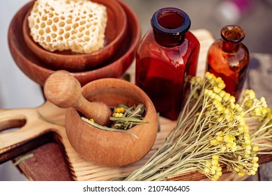 july arenarium, helichrysum arenarium, dwarf everlast, immortelle, curry plant, italian strawflower dry herbs in a mortar. and honey in honeycombs. Ingredients for ecological natural cosmetics