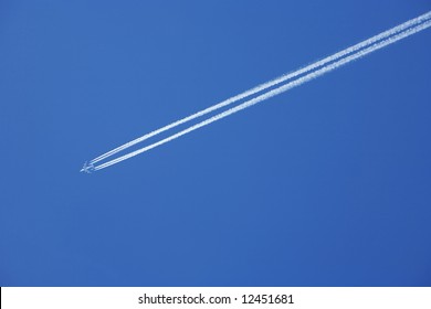 A Jumbo Jet Flies Across A Blue Sky Leaving Vapour Trails