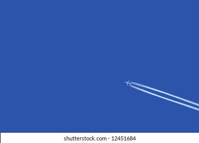 a jumbo jet flies across a blue sky leaving vapour trails