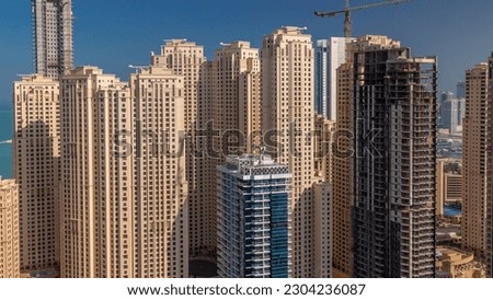 Jumeirah Beach Residence and original architecture yellow towers in Dubai aerial timelapse. Residential area on a seaside near Dubai marina with skyscraper under construction