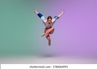In jump. Beautiful girl dancing hip-hop in stylish clothes on colorful gradient background at dance hall in neon light. Youth culture, movement, style and fashion, action. Fashionable bright portrait. - Shutterstock ID 1786064993