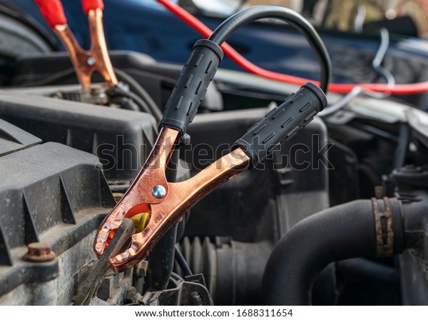 Jump cables on car low power\
battery. Black and red. Broken car start attempt. Selective\
focus.