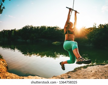 Jump Into The Water. A Woman Is Resting On The Lake. A Swing From A Rope And A Stick. Active Recreation In Nature. Summer Fun. A Woman Is Riding A Swing. Fisheye Lens.