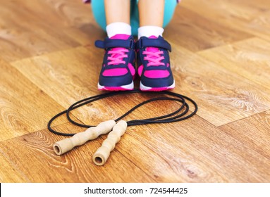 Jump rope on wooden background and sneakers.
