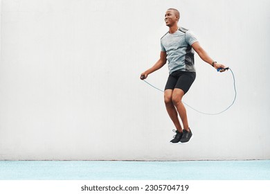 Jump, rope and space with black man skipping in stadium for sports, workout and cardio. Performance, health and body with male athlete training on track for strong, mockup and exercise by wall - Powered by Shutterstock