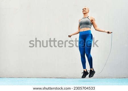 Jump, rope and woman skipping against space in stadium for sports, workout practice and cardio. Performance, health and body with female athlete training on track for strong, mockup and exercise