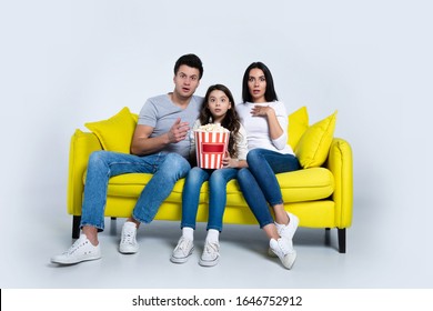 A Jump Scare. Portrait Of Scared Family Sitting At Home And Watching Scary Movies On Television While Eating Popcorn.	