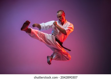 In a jump. Young martial artist in white kimono practicing flying kicks on gradient pink background. Karate, judo, taekwondo sport. Concept of martial art, combat sport, energy, fit, ad - Powered by Shutterstock