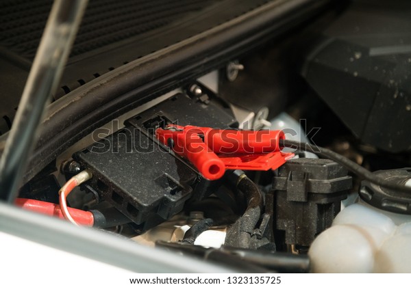 Jumper cable attached under car hood to help\
start car engine. Car repairs\
workshop
