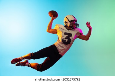 Jumping, flying. Portrait of male american football player catching ball in jump isolated on blue background in neon light. Concept of sport, movement, achievements. Copy space for ad - Powered by Shutterstock