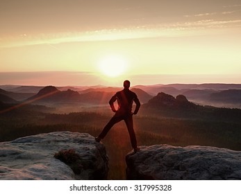 Jumping hiker in black celebrate triumph between two rocky peaks. Wonderful daybreak. - Powered by Shutterstock