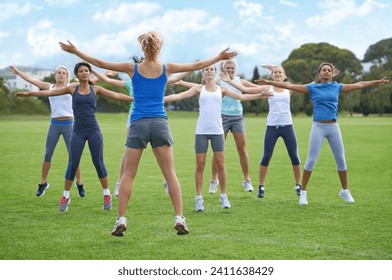 Jumping jacks, women and group outdoor for exercise on sports field and energy for cardio in fitness class. Health, wellness and training together, athlete team workout in park and physical activity - Powered by Shutterstock