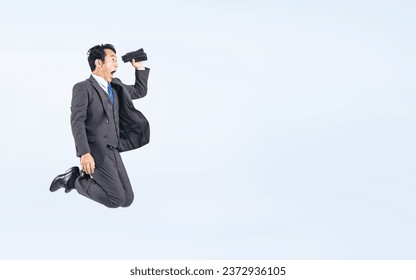 Jumping Middle aged Asian businessman with binoculars. - Powered by Shutterstock