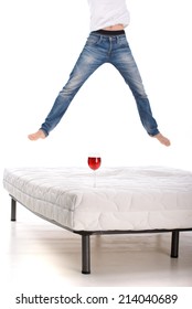 Jumping on the mattress. Young man jumping on the mattress, while the glass of wine stand on the mattress and not inverted isolated on white background
