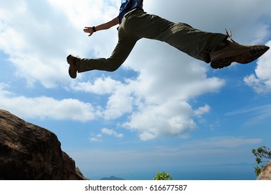 Jumping over precipice between two rocky mountains. freedom, risk, challenge, success concept