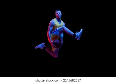 Jumping. Portrait of sportive man, professional basketball player playing basketball isolated on dark background in neon light. Concept of sport, achievements, competition, hobby, active lifestyle. - Powered by Shutterstock