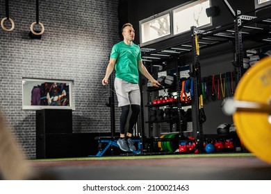 Jumping Rope. Athlete Man Working Out On A Skipping Rope. Beautiful Sports Male Person Doing Exercises With Jumping Rope In Modern Gym Space With Colorful Equipment, Worming Up For Training