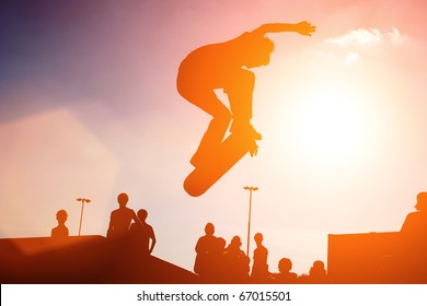 Jumping skateboarder silhouette over sunset sky background - Powered by Shutterstock