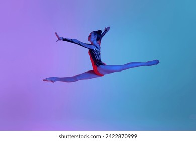 Jumping in a twine. Rhythmic gymnast in motion, teen girl performing against gradient studio background in neon light. Concept of sport, beauty and grace, competition, art, youth, hobby - Powered by Shutterstock