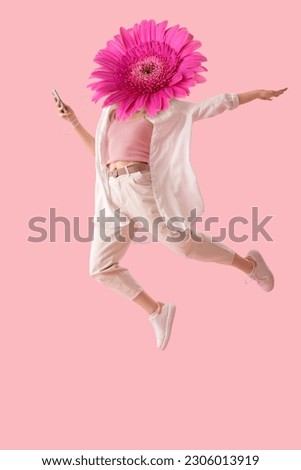 Jumping woman with gerbera flower instead of her head on pink background