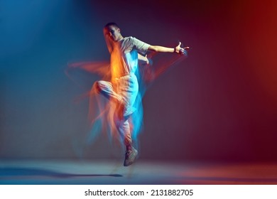 Jumping young girl with short hair cool dancing in colorful neon light. Contemporary dance school ad. Long exposure - Shutterstock ID 2131882705