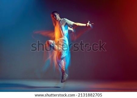 Jumping young girl with short hair cool dancing in colorful neon light. Contemporary dance school ad. Long exposure