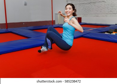 Jumping Young Woman On A Trampoline In Amusement Park