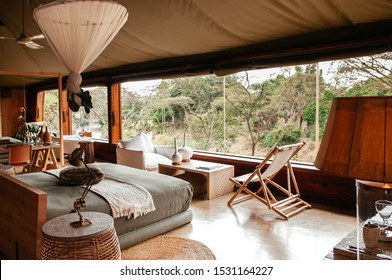 JUN 20, 2011 Serengeti, Tanzania - African Boho Style Contemporary Tent Camp Lodge Bedroom Interior With Natural Wooden Chair Set And Bed With  Canopy Mosquito Net And Forest View Through Bay Window