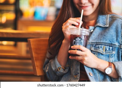Jun 20th 2020 : Close up of a woman holding and drinking iced coffee at Starbucks coffee shop , Chiang mai Thailand 
