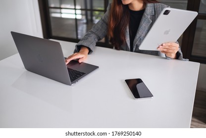 Jun 27th 2020 : A business woman holding and using Apple New Ipad Pro 2020 tablet pc , Apple MacBook Pro laptop computer and Iphone 11 Pro Max smart phone , Chiang mai Thailand