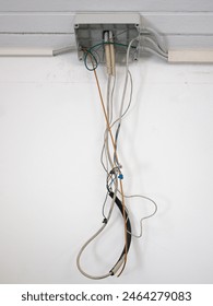 junction box of an open electrical system with dangling wires, white wall background