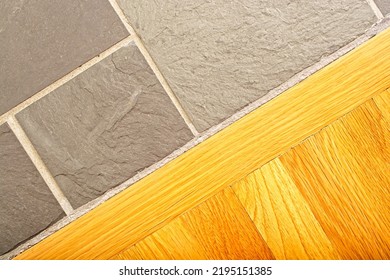 Juncture of oak hardwood boards and grouted slate tile floor covering. Top down view. Natural oak finish, grey slate - Shutterstock ID 2195151385