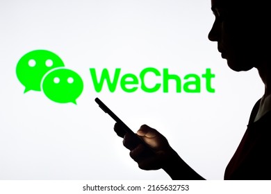 June 10, 2022, Brazil. In this photo illustration, a woman's silhouette holds a smartphone with the WeChat logo in the background