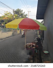 June 18, 2022. Sidoarjo, Indonesia. Smoke Rises Into The Air, From The Chicken Meat That Was Burned By A Woman Selling Chicken Satay, Which Is On The Side Of The Village Road.