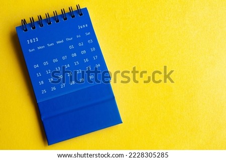 June 2023 blue desk calendar on yellow cover background.