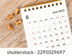 June 2023 Monthly desk calendar for 2023 year with pin on wooden background.
