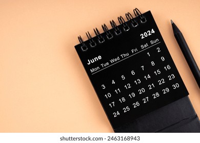 June 2024 Black spiral desktop calendar and wooden pencil on yellow background. - Powered by Shutterstock