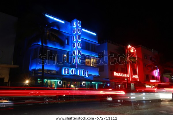 JUNE 24 2017 - CALLE OCHO, MIAMI BEACH, FLORIDA \
The Colony and the Boulevard hotels are lit up in red and blue neon\
on South Ocean Drive with car lights streaking by in a long time\
exposure at night.
